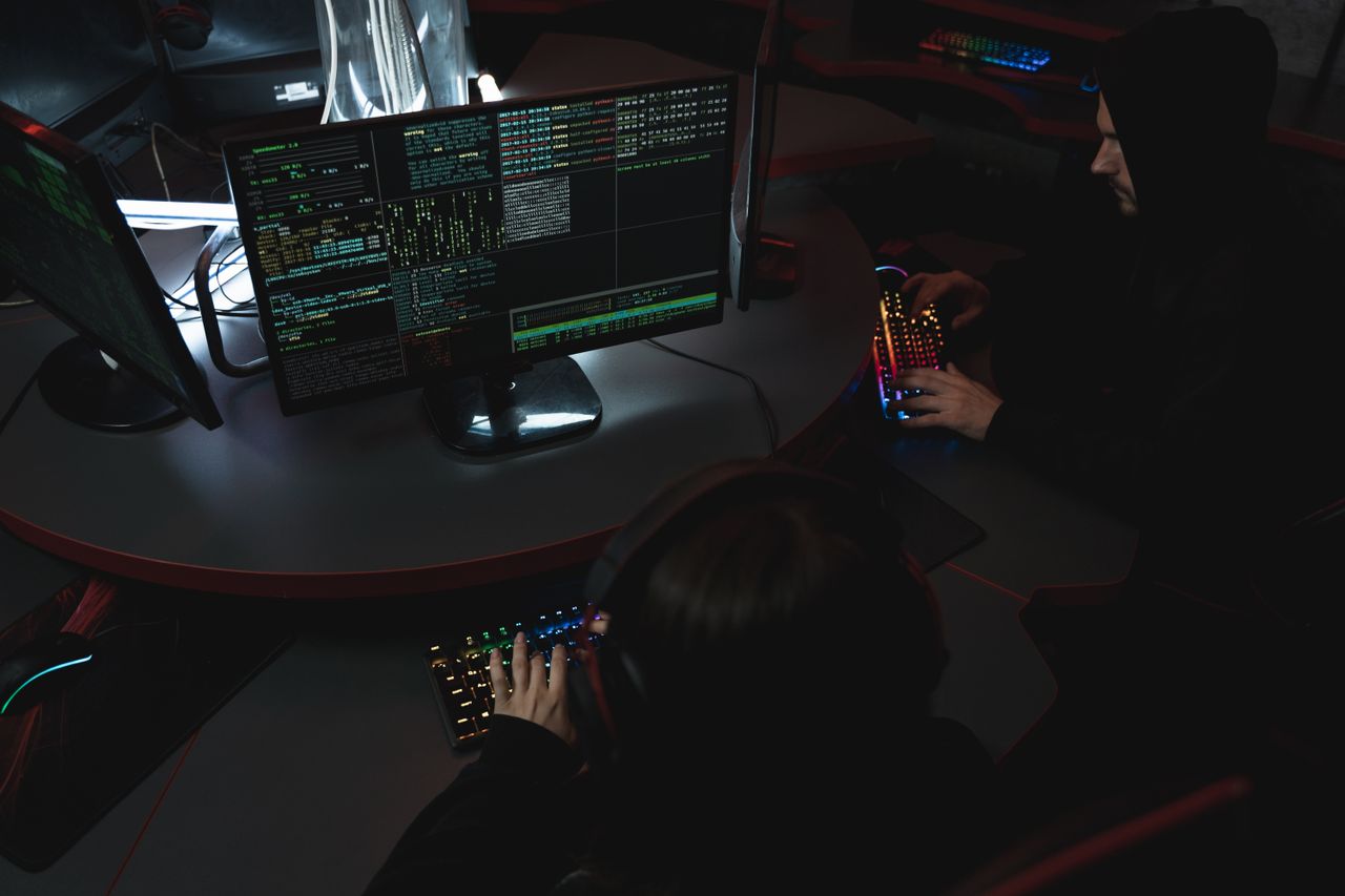 About A group of people in a dark room working on computers, related to cybersecurity.